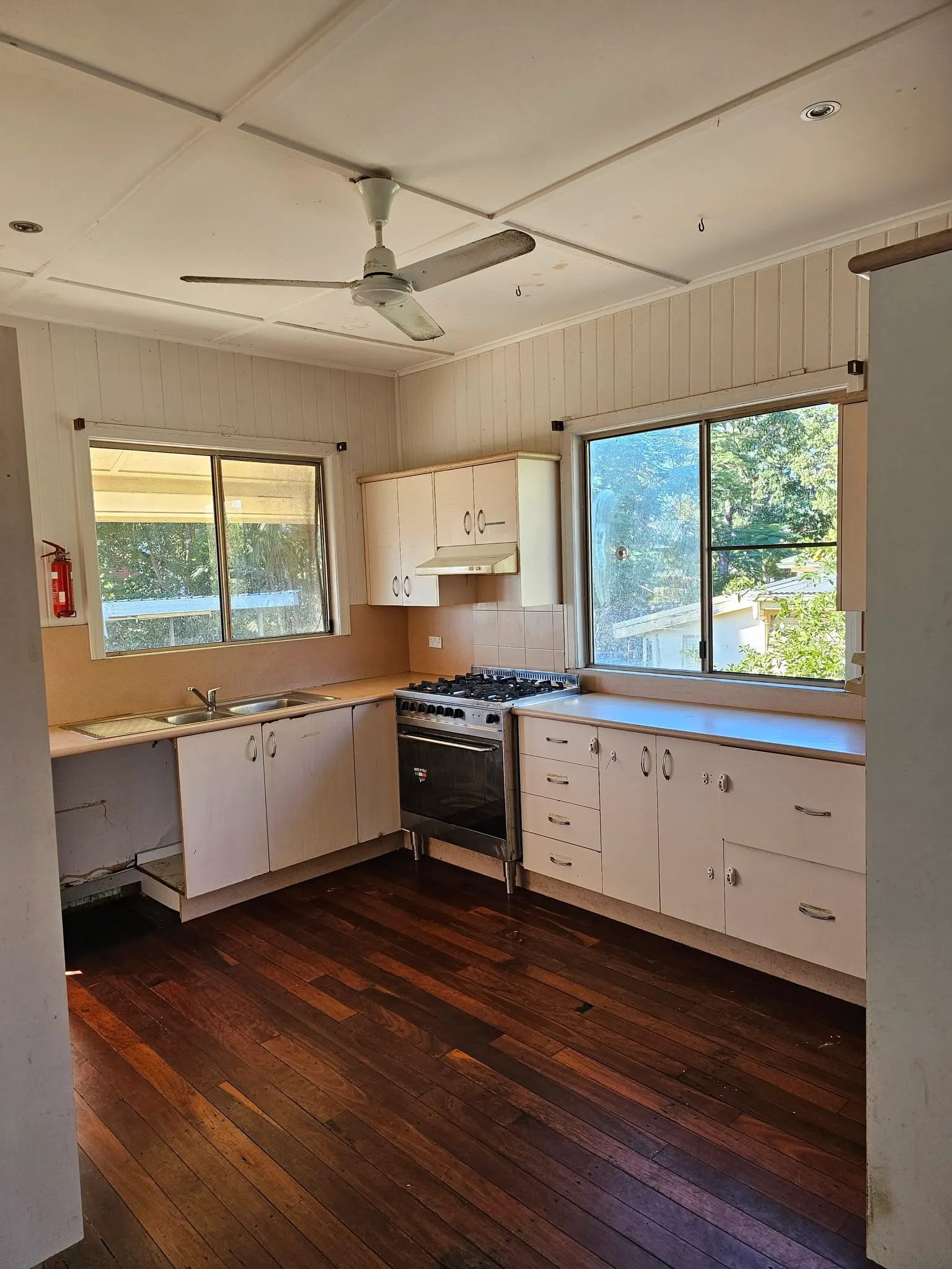 Empty Queenslander kitchen with timber floor, gas oven and ceiling fan